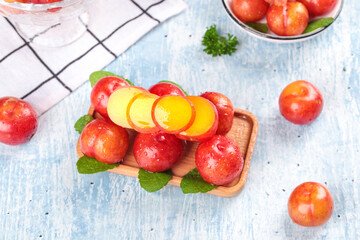 Fresh Red Guangdong Plums on Wooden Plate with Mint Leaves - Crisp Sour March Fruits