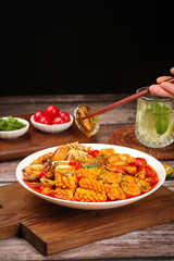 Spicy seafood dish with fresh shellfish and sauce being served on rustic wooden table