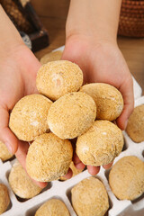 Fresh Golden Egg Pasta Balls Held in Hands with Flour Coating