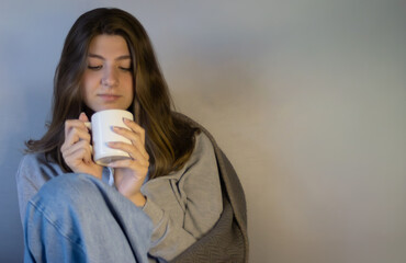 Young woman drinking coffee in neutral tone background. Space for text