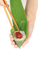 Traditional Tamale Wrapped in Fresh Green Leaves with Rice and Red Filling Held by Hands