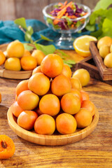 Fresh Xinjiang Apricots in Wooden Bowl - Small Orange Stone Fruits on Rustic Kitchen Table