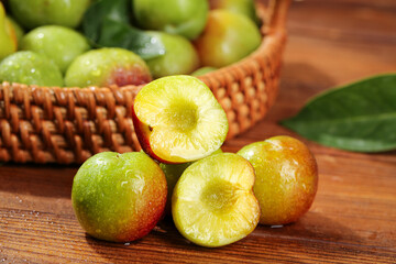 Fresh Cut Plums Displaying Yellow Flesh in Rustic Basket on Wood Table
