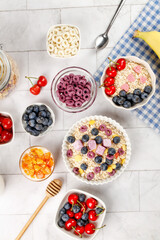 Healthy breakfast bowls with oats, yogurt, berries and fruit on white marble background