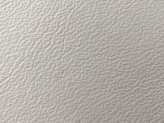 Close-up of quilted leather or vinyl upholstery, a light-colored seamless background with diamond stitching.
