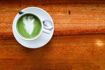 Top View Artistic Matcha Latte with Leaf Art on Wooden Surface
