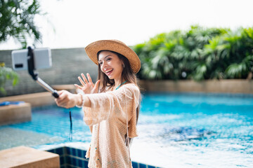 Young Hispanic Gen Z Woman in Swimwear Creating Travel Vlog as Influencer by Resort Pool in Summer
