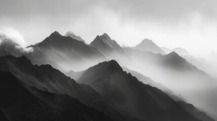 black and white mountain range with misty foggy atmosphere, dramatic landscape photography showcasing rugged peaks and mysterious moody nature scene in monochrome
