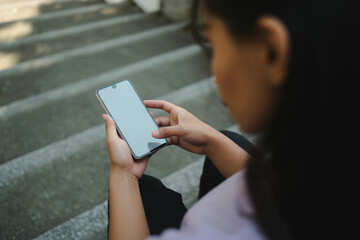 Young woman using a smartphone while sitting on outdoor stairs