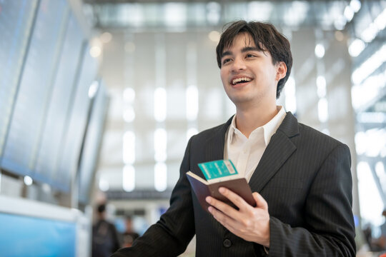 Asian businessman passenger checking departure boarding pass in airport.  - Powered by Adobe