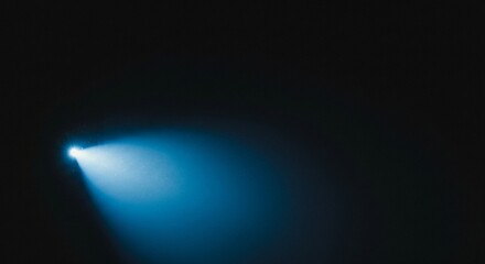 A bright blue light beam illuminates a dark empty space with soft atmospheric glow