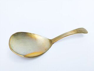 old brass spoon with a slightly tarnished surface and a simple engraved handle, isolated on white background.