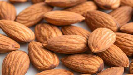 Fototapeta premium A pile of brown almonds, a healthy and organic snack, is isolated on a white background in a close-up macro shot