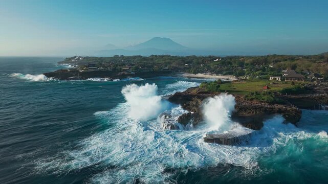 Drone video of big waves crashing at Devils Tears, dream beach with Mount Agung volcano on Nusa Lembongan island near Bali in Indonesia. 