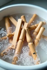 Close-up shot of wooden pegs being washed in a basin of soapy water, bubbles visible  Clean laundry essentials, preparation for drying  ,  bright,  task,  cleaning supplies