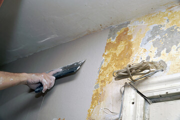 A man plastering a wall with a spatula