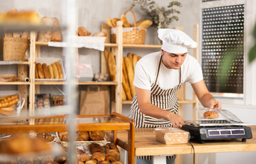 Young baker weighs fresh croissants on a scale and places them in a plastic container
