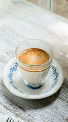 Cup of coffee latte  served on the white plate on a wooden table in coffee shop. 