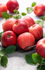 Fresh red apples resting on rustic metal plate with green leaves