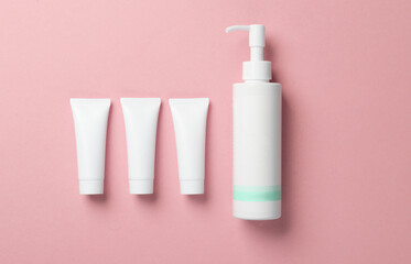 White cream tube and lotion dispenser on pink background