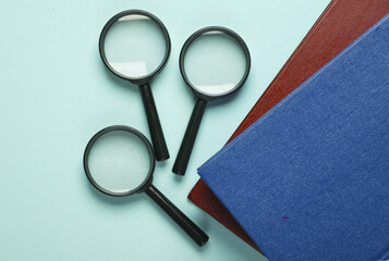 Fototapeta premium Magnifiers with books on a blue background. Education concept