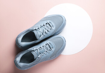 Blue sneakers on a white circles. Pink background. Creative idea. Fashion concept. Top view