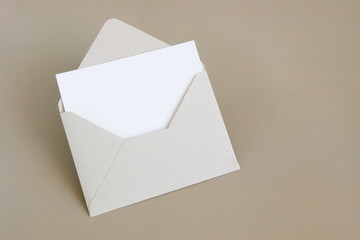 Beige envelope with blank paper card mockup  inside top view on beige background . Copy space.Minimalist aesthetic wedding invitation mockup, greeting card, holiday concept.