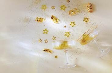 Champagne glasses and Christmas, festive , party decoration gold balls, confetti, stars, serpentine top view on beige background.New Year, holiday, birthday, wedding mockup ,template with copy space.