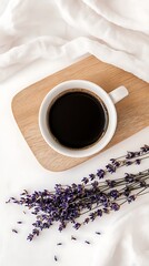 Black coffee cup on wood with dried lavender flowers, draped on white cloth