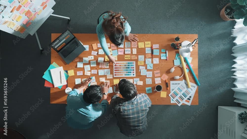 Poster top down view of business team with casual outfit looking laptop screen and sharing idea. aerial vie