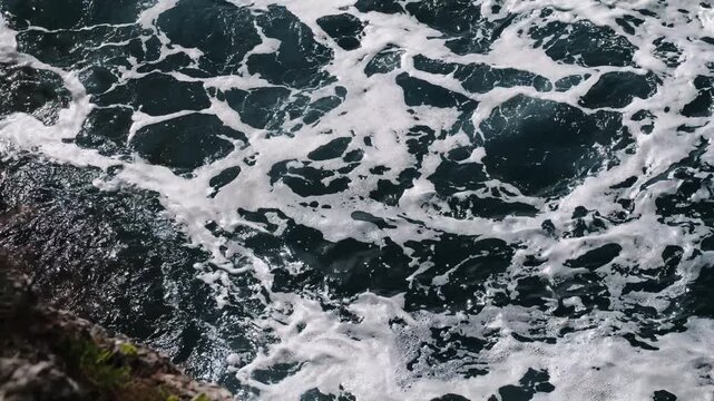 Close-up of Adriatic waves foaming on the surface in Budva, Montenegro. Horizontal 4k footage. Top view of Rocky cliff and sea waves