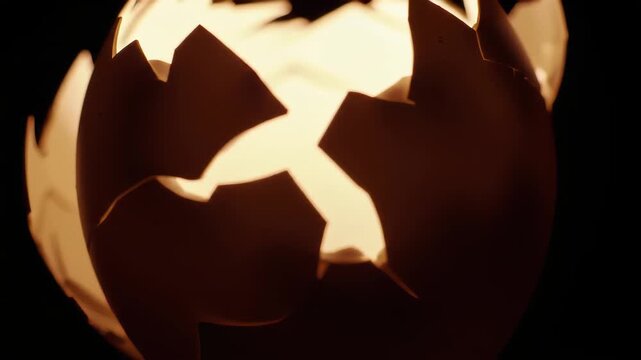 Dramatic Close Up of A Cracked Egg Shell with Bright Light Glowing Through The Openings