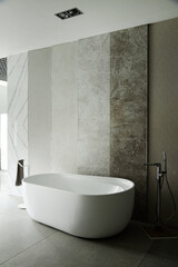 Modern bathroom featuring freestanding oval bathtub positioned against wall with large textured...