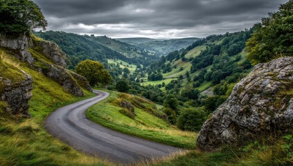 Winding road through a lush valley under a dramatic sky