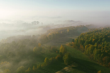 Obraz premium Low clouds blanket autumn trees and fields at sunrise