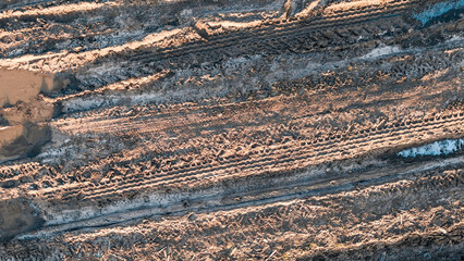 Muddy puddles and tire tracks creating rough terrain on dirt road