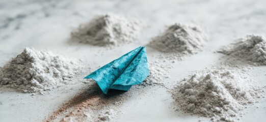 Obraz premium Light gray powder piles surround a teal paper airplane