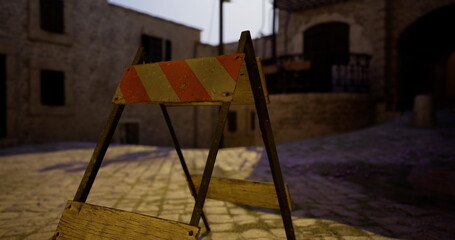 A traffic barrier rests on a cobblestone path in a tranquil, dimly lit street. Surrounding buildings emit a rustic charm, creating an atmospheric evening scene.