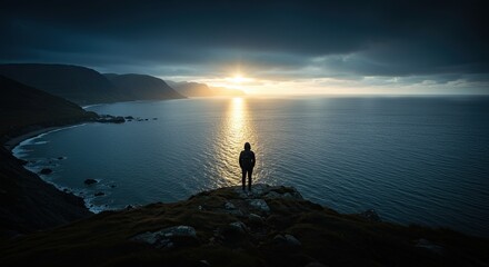 Person Standing on Cliff Overlooking Calm Blue Ocean at Sunset