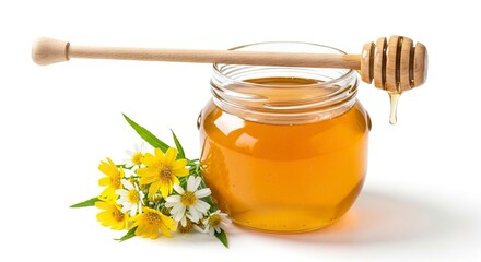 A clear glass jar filled with golden honey a wooden dipper resting on top with a drip and a cluster of yellow and white flowers on a white surface