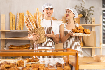 Two sellers in bakery stand near counter, wait for visitors to supplement baking stocks with...