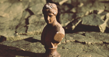 This detailed bust, depicting a classic figure, stands gracefully atop a rugged stone surface.