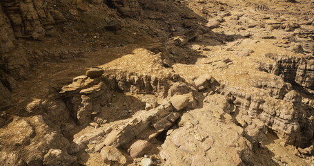Unique rock formations dominate a dry, rugged landscape under bright sunlight. The detailed textures showcase various geological layers, offering insight into the areas natural history and erosion.