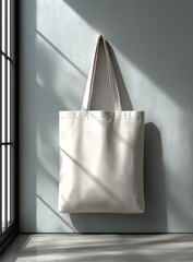 Simple white tote bag hangs on light-grey wall