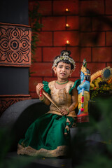 Adorable Indian girl in temple background with Krishna idol, concept of culture, tradition and...