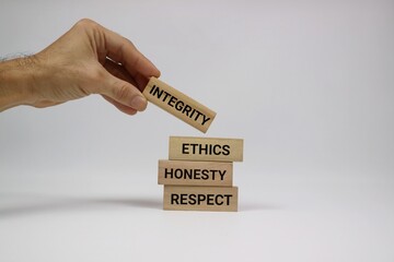 Hand Arranging Wooden Blocks with Ethics, Honesty, and Integrity Texts. Isolated on white background