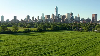 City skyline emerges behind lush green fields, a serene urban-rural contrast - Powered by Adobe