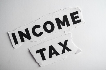 Income Tax Concept with Torn Paper Text on White Background