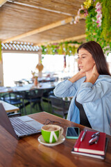 Freelancer suffering neck strain during remote work, battling project pressures in crowded cafe...