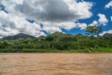 Heavy rain over the Amazon River and forest, with a small boat navigating the water amidst the storm